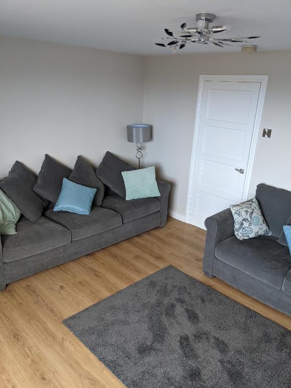 uma sala de estar com um sofá cinzento e um tapete em Seaview Ballintoy em Ballintoy