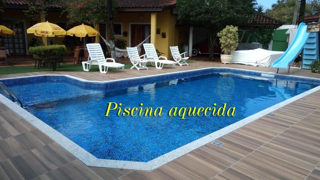 a pool with chairs and a slide next to a house at Pousada Villa Virgínia Guarujá in Guarujá