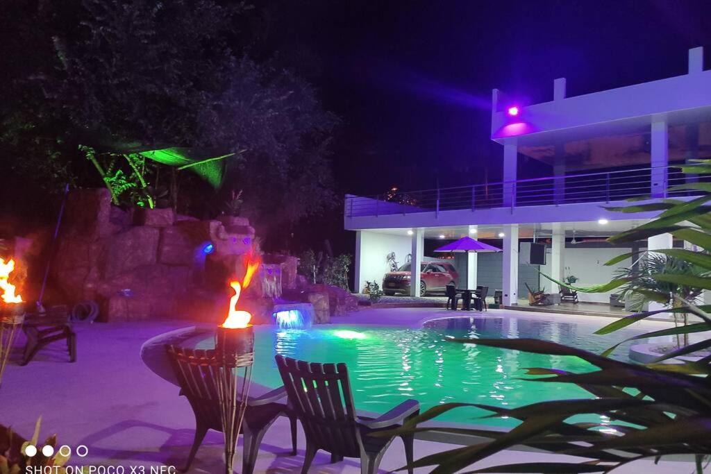 a swimming pool at night with chairs and a house at Quinta SHADDAI MELGAR in Melgar