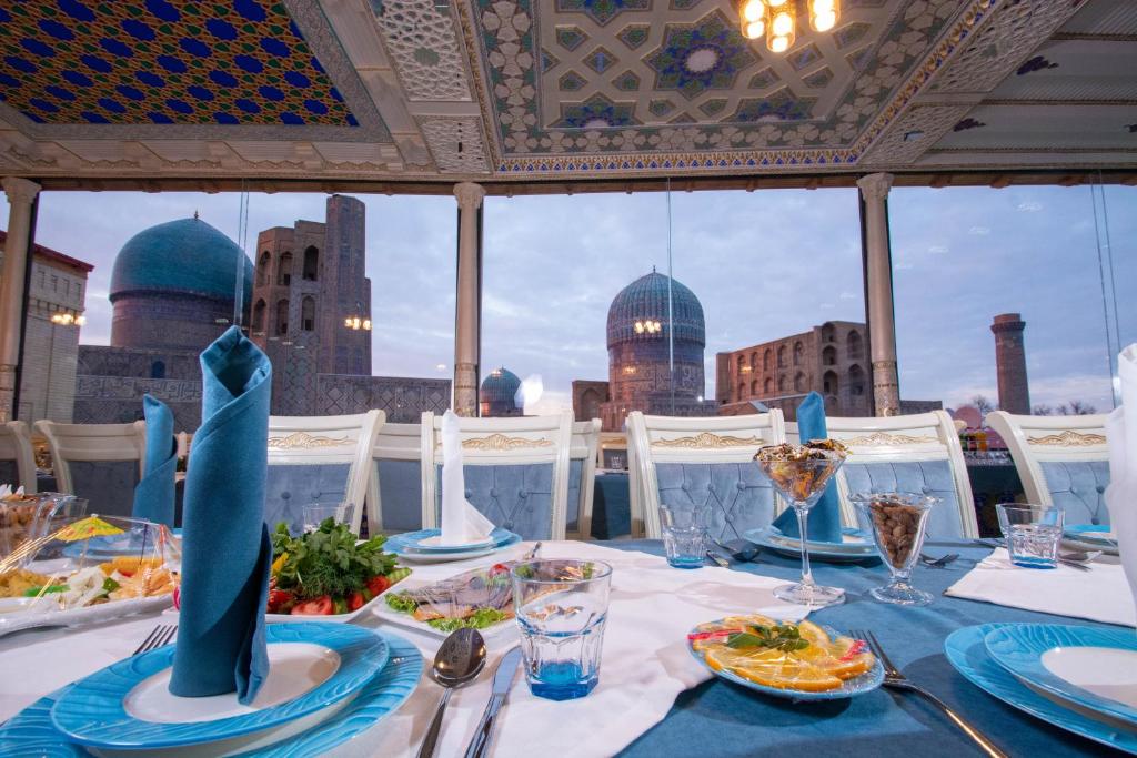 a table with plates of food and a view of the city at Bibikhanum Hotel in Samarkand