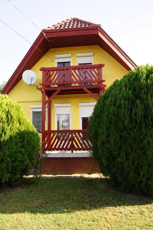 Una casa amarilla con un gran balcón. en Apartman Susy, en Balatonszentgyörgy
