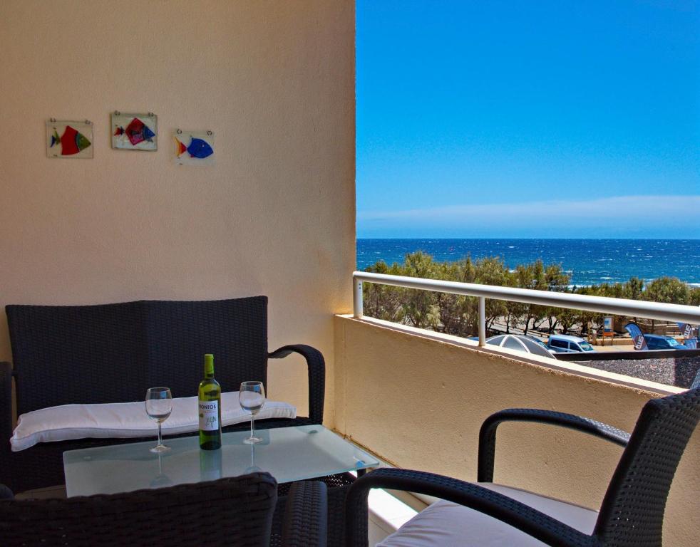 a balcony with a table and two wine glasses at MEDANO4YOU Cabezo at Marineda in El Médano