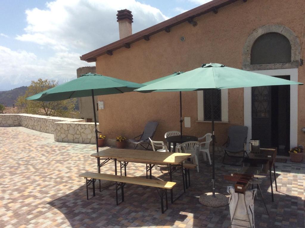 un patio avec des tables et des parasols en face d'un bâtiment dans l'établissement da sciuri case vacanza Barisciano, à Barisciano