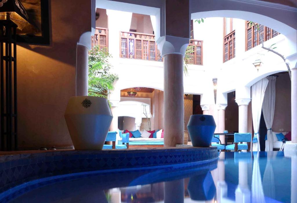 a swimming pool with blue chairs and a building at Riad Turquoise in Marrakech