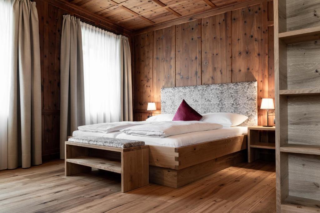 a bedroom with a bed and a wooden wall at Garni Hotel Tauber in Bressanone