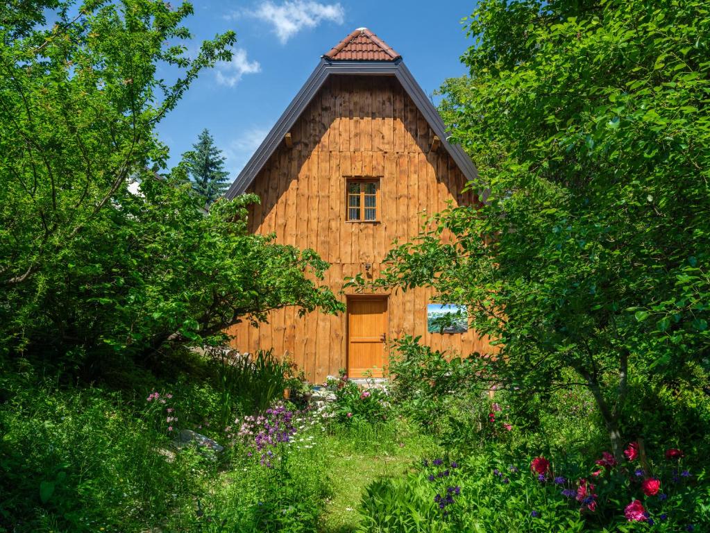 a wooden barn with a door in a garden at Yeti Cabin in Plitvica Selo