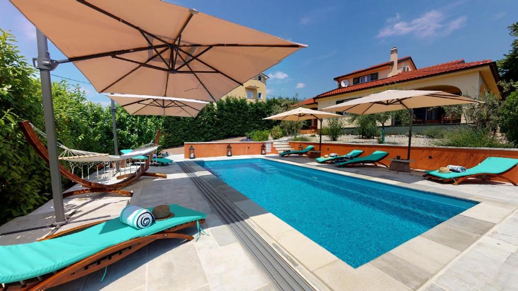 - une piscine avec des chaises et des parasols à côté d'une maison dans l'établissement Villa Oasis Kostrena, à Kostrena