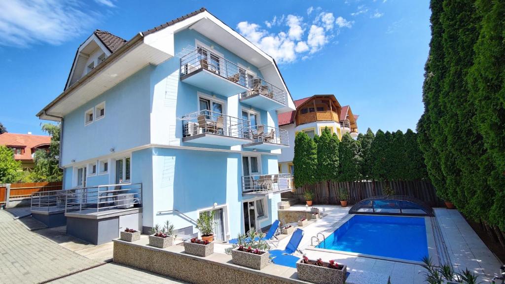 a white house with a swimming pool in front of it at Blue Mediterran Apartment House in Balatonfüred