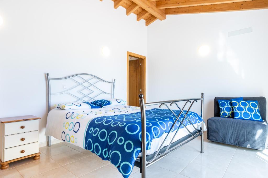 a bedroom with a bed and a chair at Villa Flavia in Aljezur