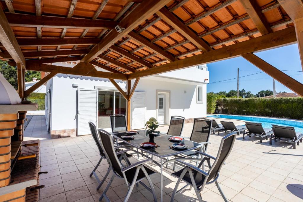 a patio with a table and chairs and a swimming pool at Villa Flavia in Aljezur