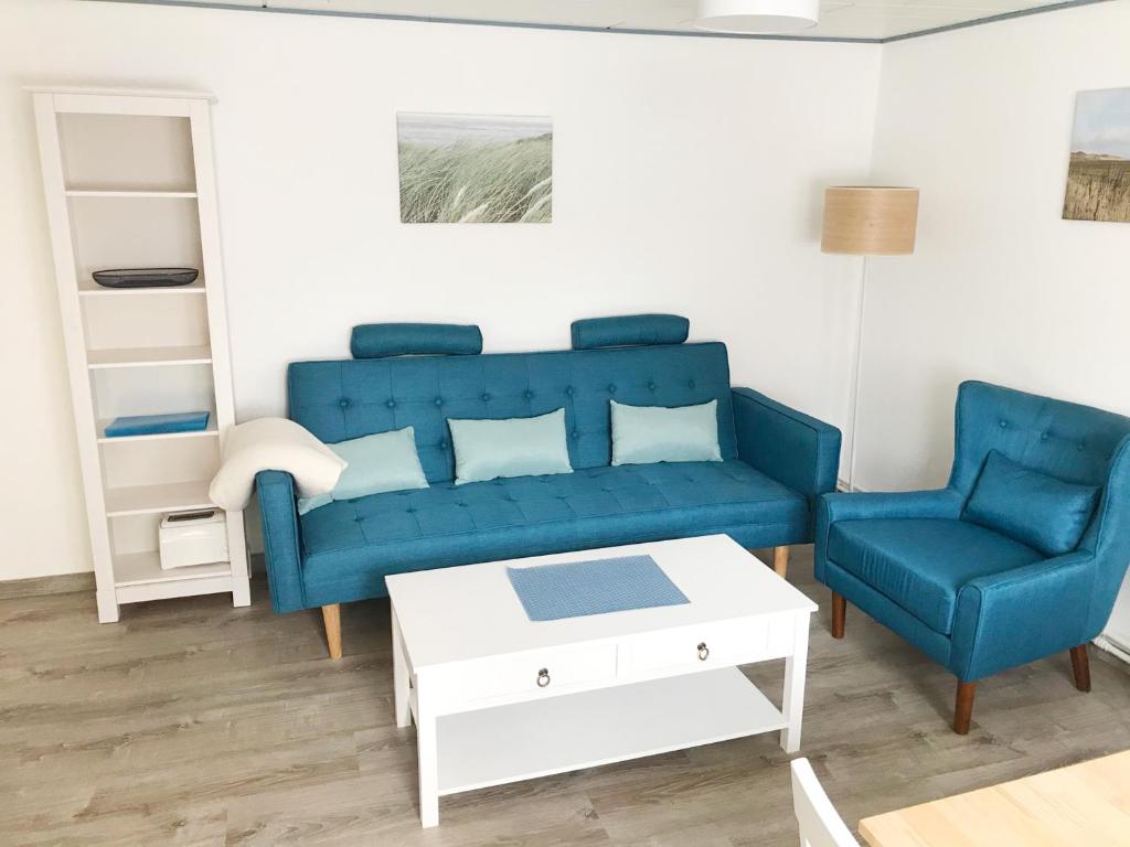 a living room with a blue couch and two chairs at Haus Frisia Ferienwohnung Frisia 3 in Norddorf