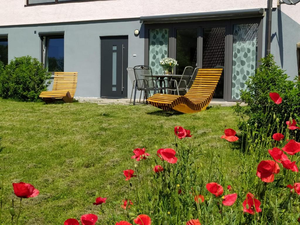 2 chaises, une table et des fleurs rouges dans la cour dans l'établissement Ferienwohnung Sanwald, à Schwäbisch Hall