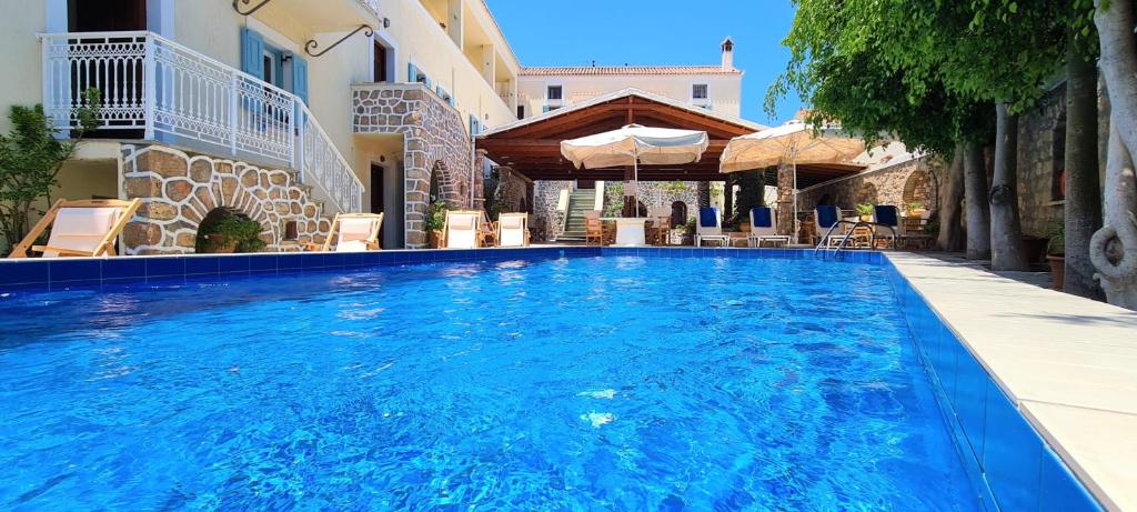a large blue swimming pool next to a building at Kastro Hotel in Spetses