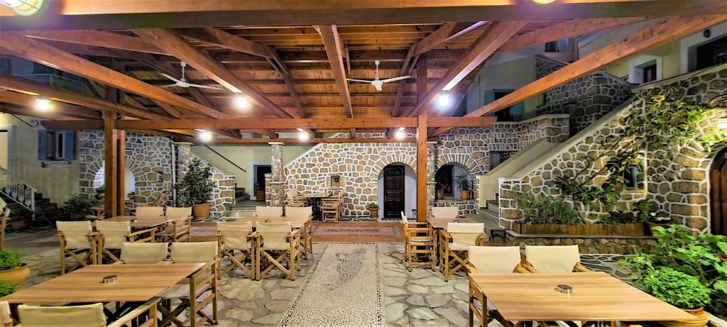 a restaurant with wooden tables and chairs and a stone wall at Kastro Hotel in Spetses