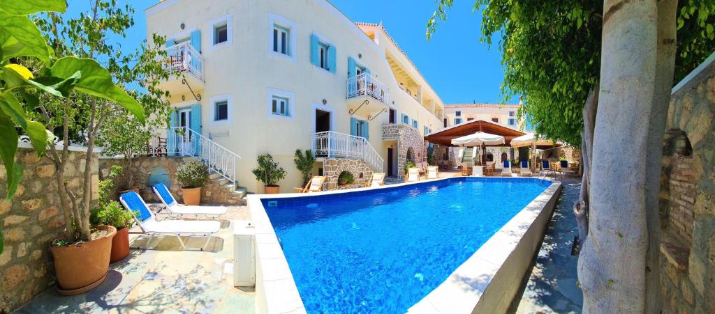 a swimming pool in front of a house at Kastro Hotel in Spetses