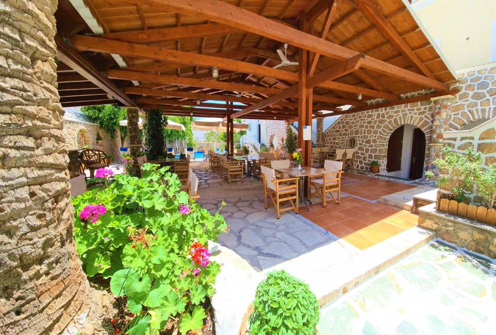 a patio with a table and chairs under a wooden roof at Kastro Hotel in Spetses