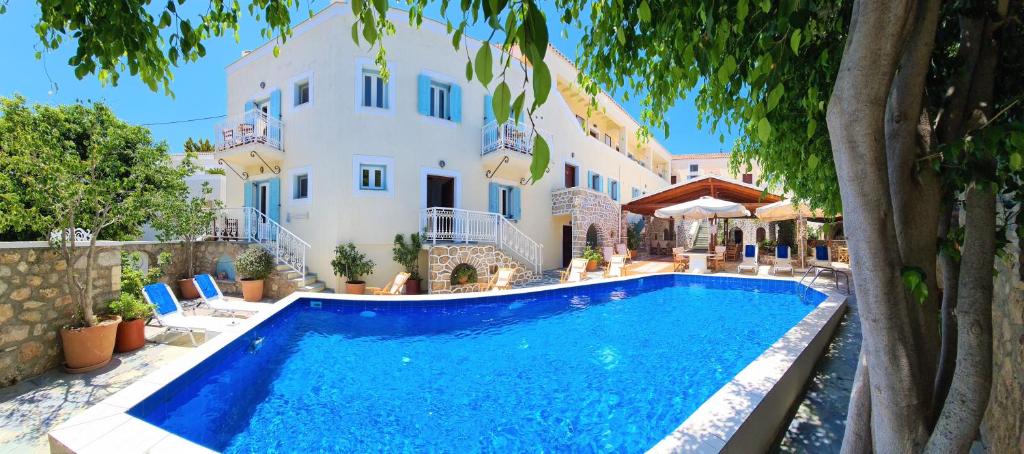 a villa with a swimming pool in front of a building at Kastro Hotel in Spetses