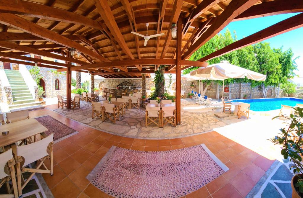 an outdoor patio with tables and chairs and a pool at Kastro Hotel in Spetses