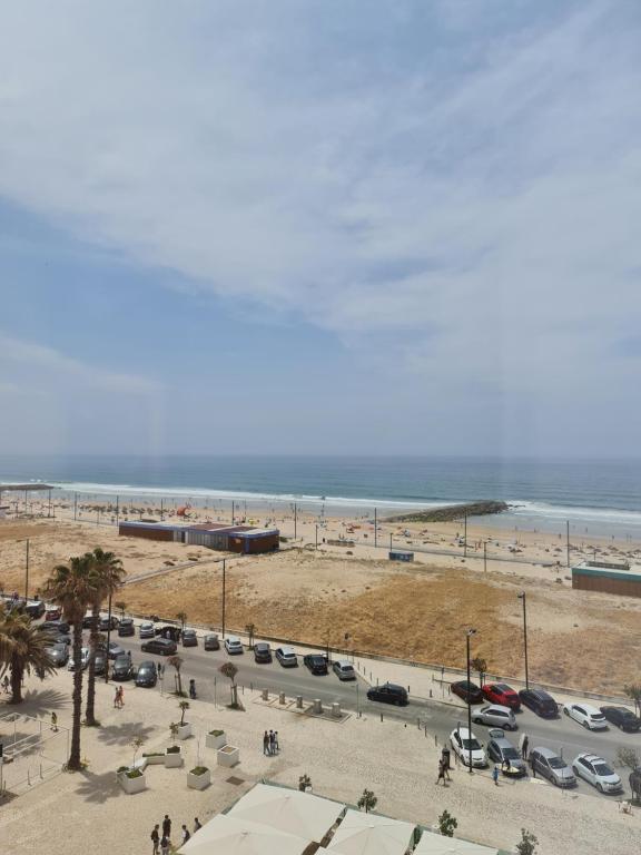 a beach with a lot of parked cars and the ocean at Casa da Praia da Costa in Costa da Caparica