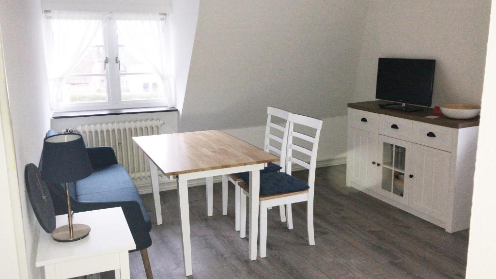 Habitación pequeña con mesa, sillas y TV. en Haus Frisia Ferienwohnung Frisia 5, en Norddorf