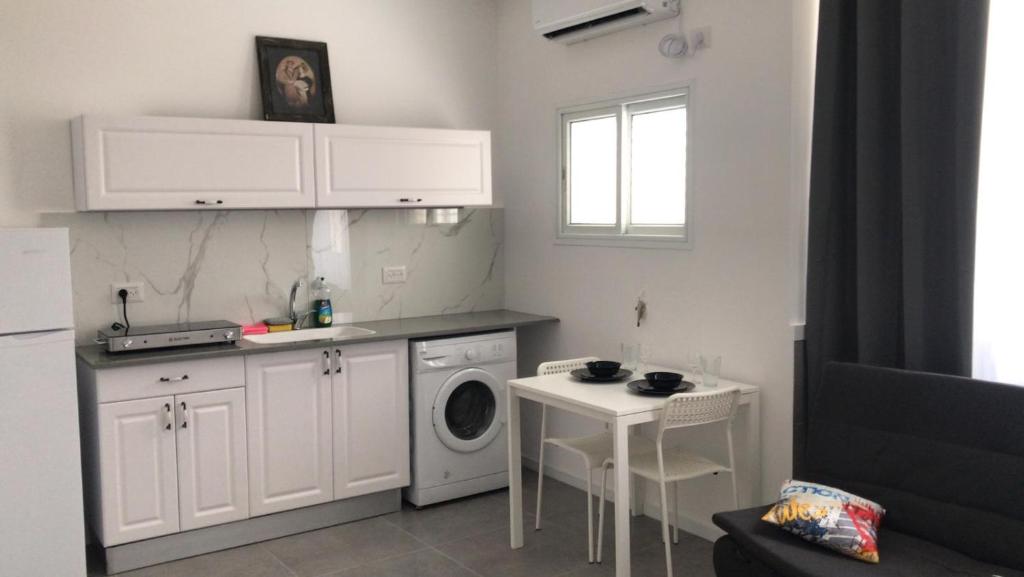 uma cozinha com uma máquina de lavar roupa e uma mesa em Isramax low-cost apartment near the sea. em Bat Yam