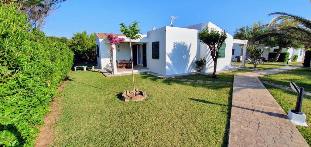 a small white house with a grass yard at Casa RISSAGA - Las Golondrinas in Cala'n Bosch