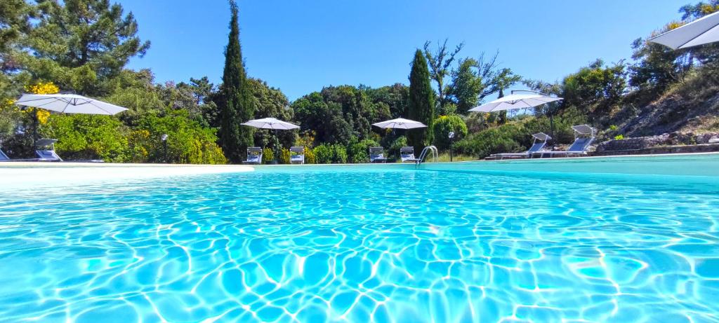 una piscina con agua azul y sombrillas blancas en Agriturismo Poggio Leone, en Gambassi Terme