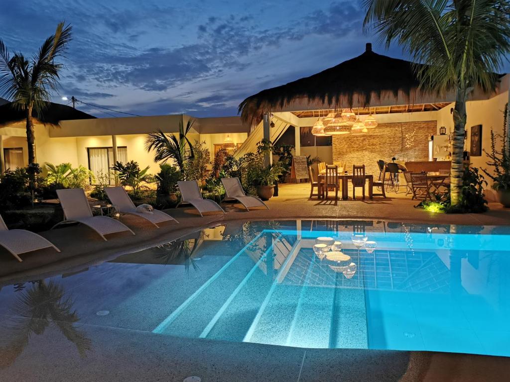 a swimming pool with chairs and a table and a house at La Maison Vanille in Ngaparou