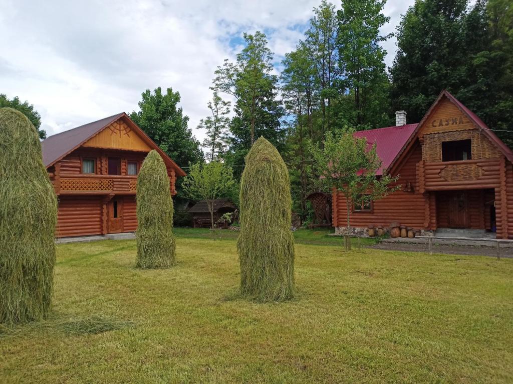 a group of trees in the grass in front of a cabin at Біля річки in Izki