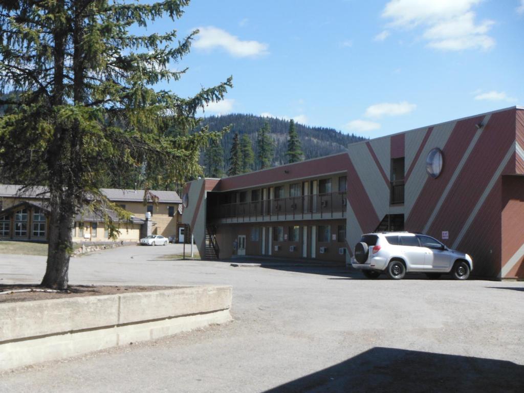 a building with a car parked in a parking lot at Tumbler Ridge Inn in Tumbler Ridge