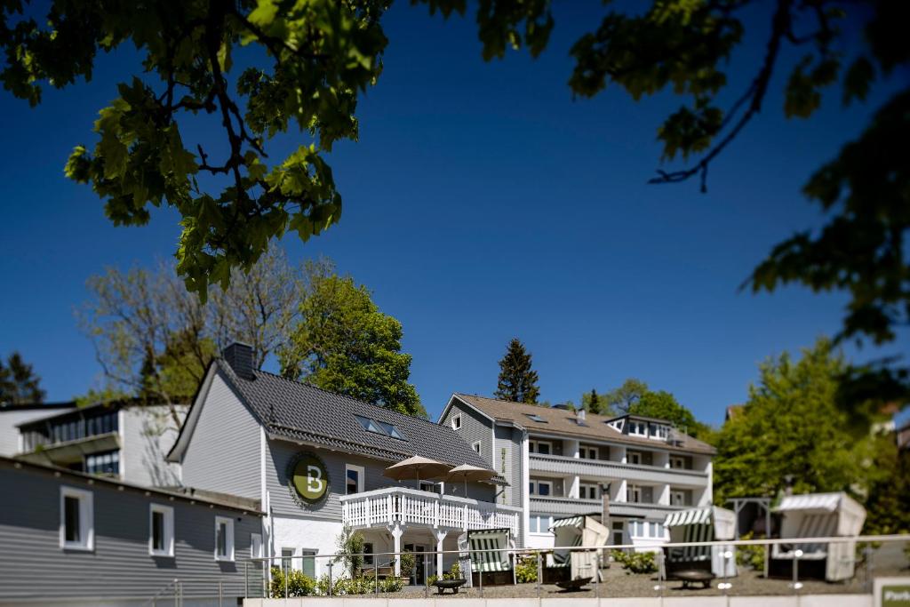 - un grand bâtiment blanc avec une terrasse couverte dans l'établissement Berg und Tal Hotel & Apartments, à Braunlage