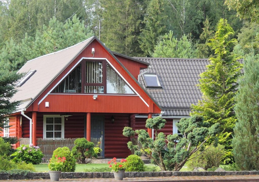 a red house with a gray roof at Cottage - Liepų Sodyba in Joniškėlis