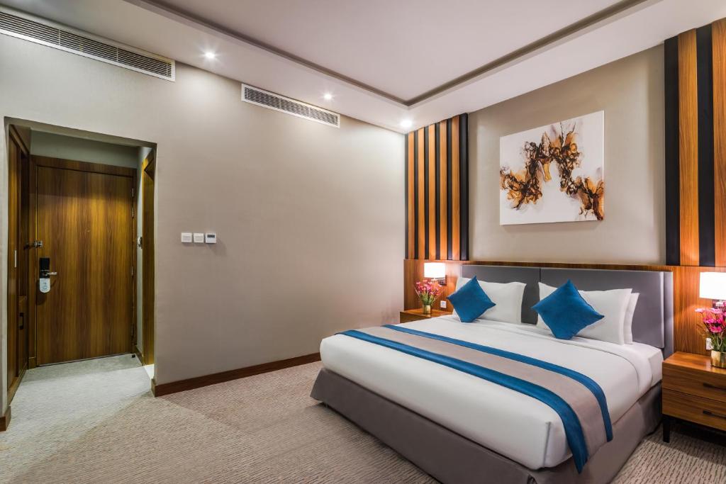 sypialnia z dużym łóżkiem z niebieskimi poduszkami w obiekcie Myrtle Hotel - Al Sahafa w Rijadzie