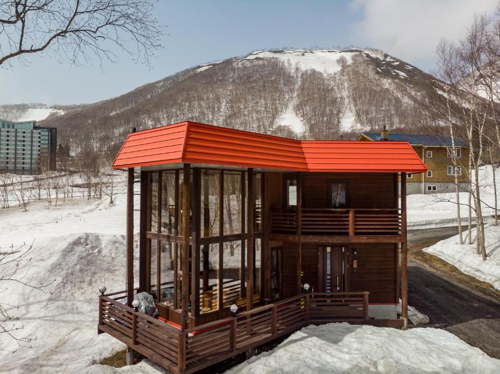 un pequeño edificio con una montaña cubierta de nieve en el fondo en Matsu House - 5 minutes away from Rusutsu Ski Resort en Rusutsu