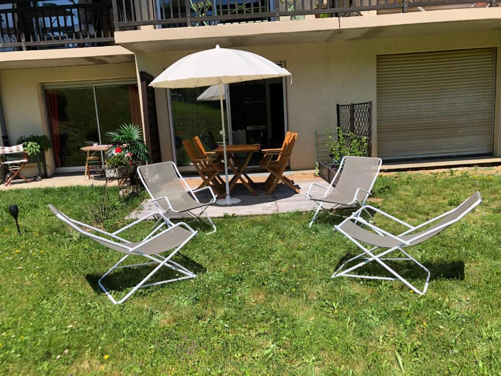 a group of chairs and an umbrella in the grass at Le petit Chamois in Saint-Gervais-les-Bains