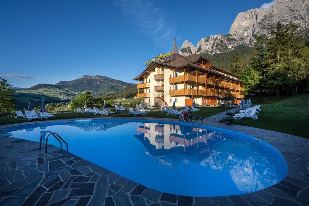a hotel with a large swimming pool in front of a mountain at Parc Hotel Miramonti in Völs am Schlern