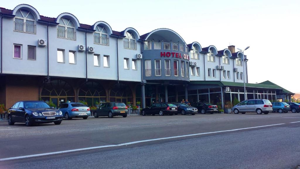 a large white building with cars parked in front of it at Hotel Oxa doo in Novi Pazar