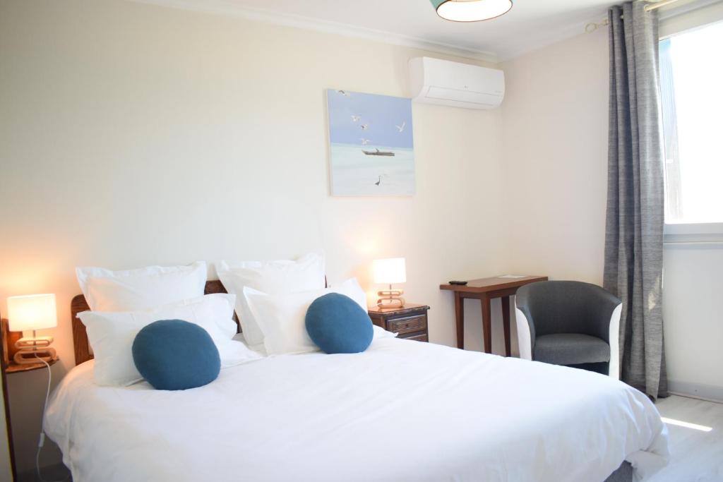 a bedroom with a large white bed and a chair at Source de la Vallée in Sadroc