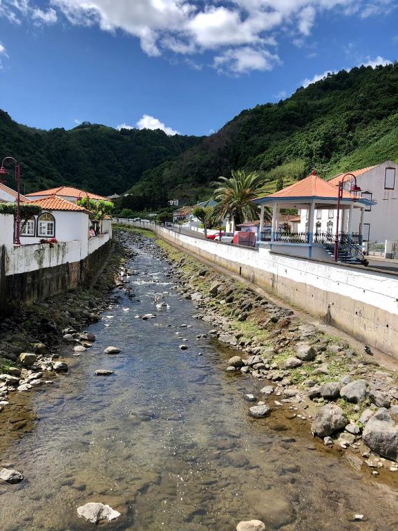 a river flowing through a town with mountains in the background at Casa Auri in Faial da Terra