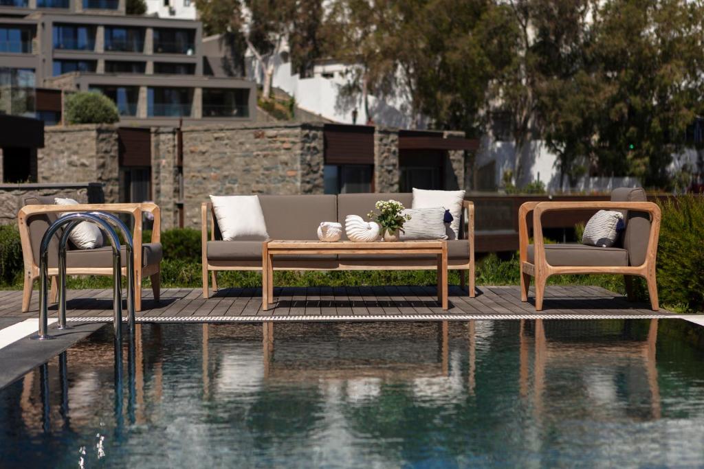 two chairs and a couch next to a swimming pool at METT Hotel & Beach Resort Bodrum in Bodrum City