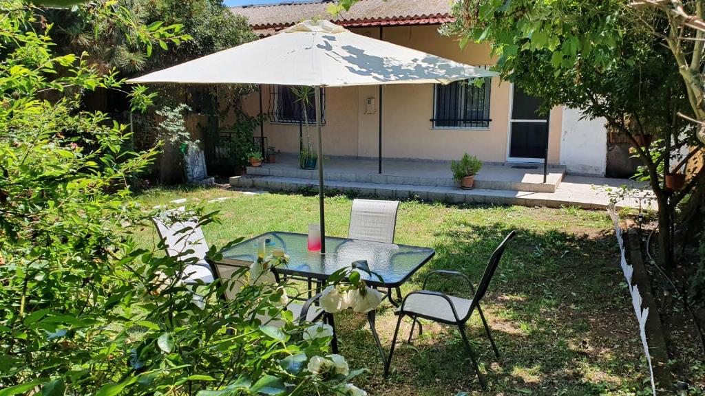 a table and chairs under an umbrella in a yard at christos cottage! comfortable and quiet! in Keramotí