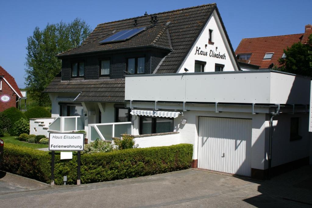 a white building with a garage in front of it at Haus Elisabeth in Carolinensiel