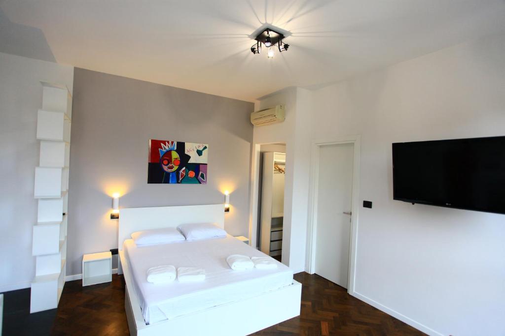 a white bedroom with a bed and a flat screen tv at B&B Allegra in Bologna