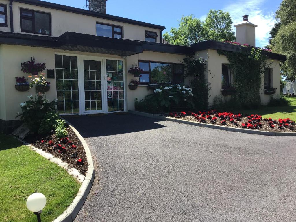 a house with flowers in front of a driveway at Aran Lodge in Bantry