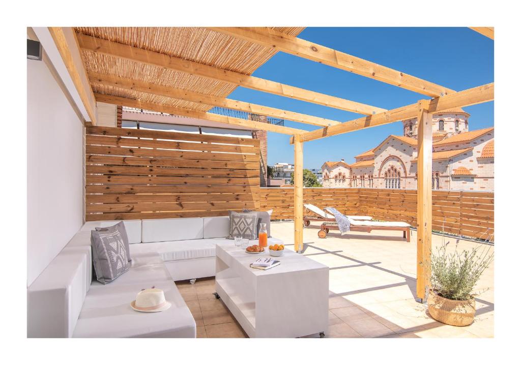 a patio with white furniture and a wooden pergola at Baulus Sun Yard in Heraklio