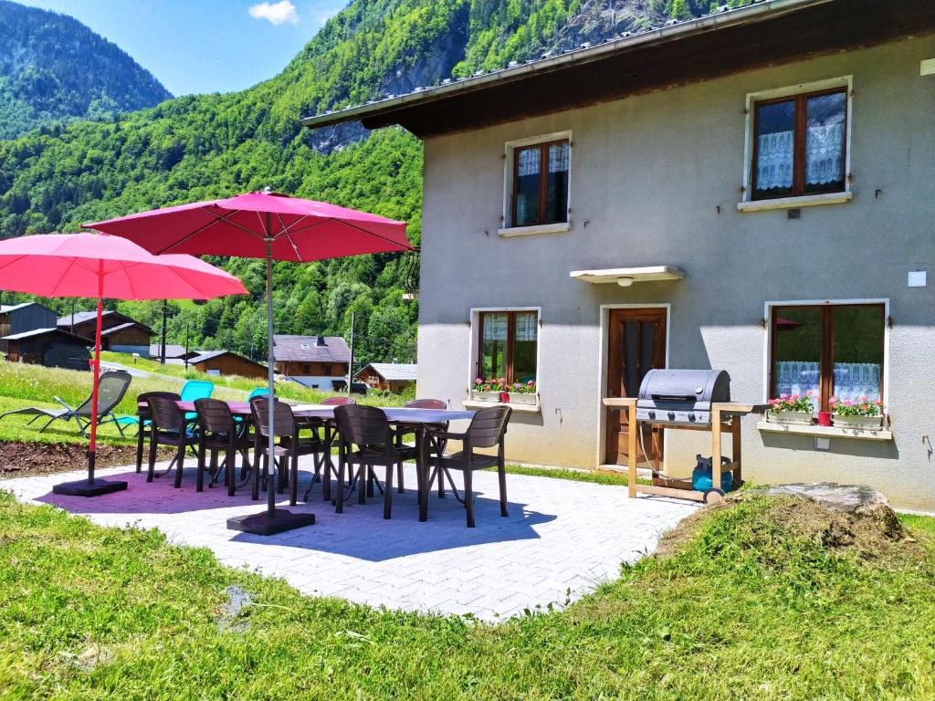 a patio with tables and umbrellas in front of a house at Le clair logis in Sixt