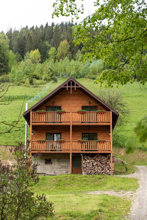 a wooden house with a deck on a hill at Villa Grace in Oryavchyk