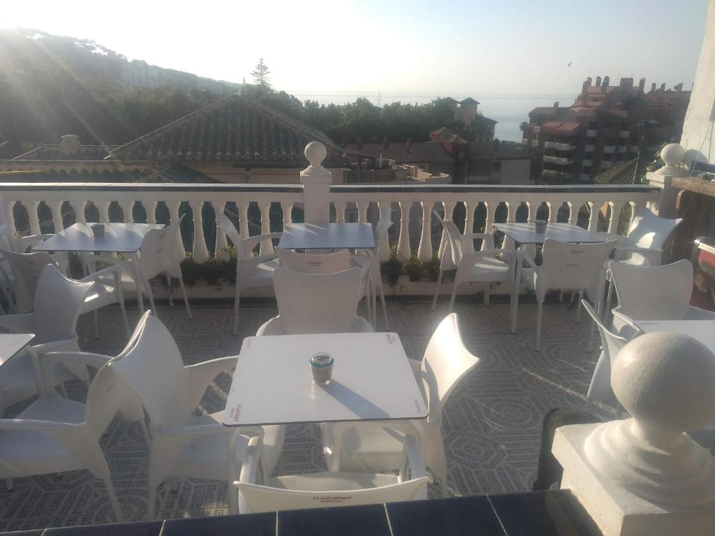 un patio con mesas blancas y sillas en el balcón en Terraza del Limonar, en Málaga