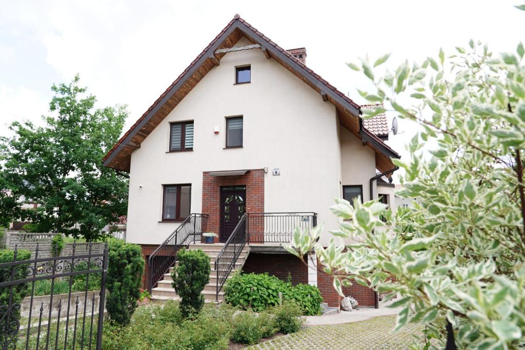 ein weißes Haus mit einer schwarzen Tür und einer Treppe in der Unterkunft Pokoje goscinne na Wodnej in Lidzbark