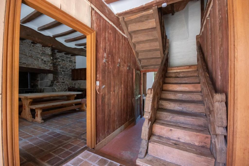 a wooden staircase in a room with a table at Manoir le Cosquer in Pommerit-le-Vicomte